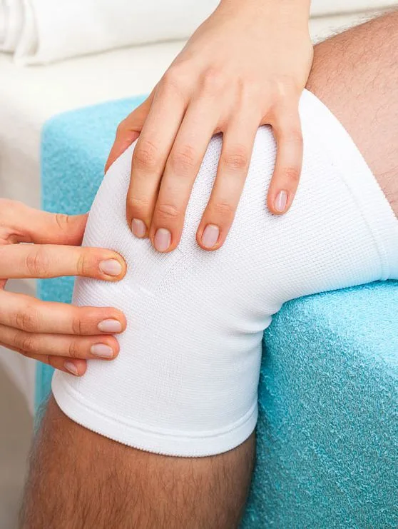 Hands assessing a patient’s knee